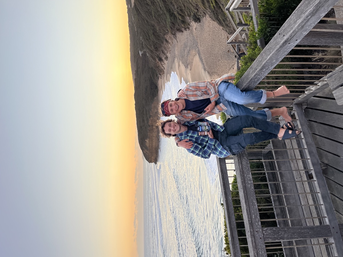 Giacomo and Isaac sitting together above Bells Beach at sunset
