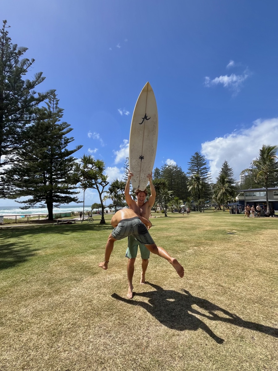 Giacomo and Isaac playing with a surfboard on the grass at Burleigh