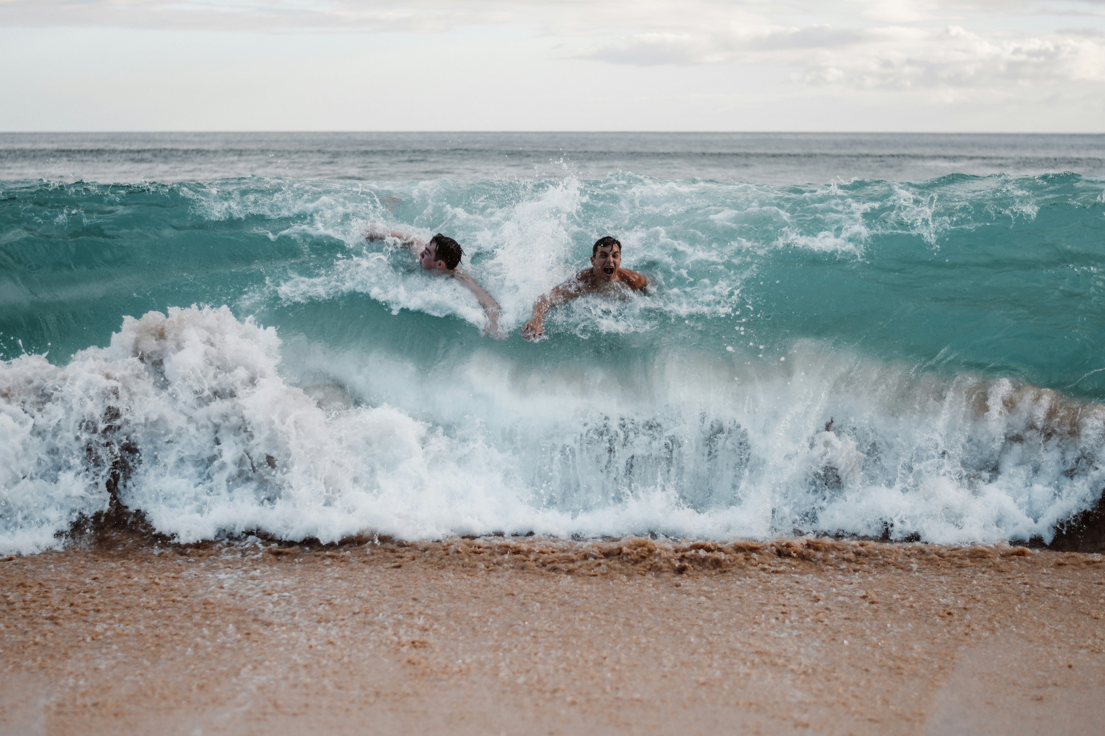 Friends laughing and playing together in an ocean wave